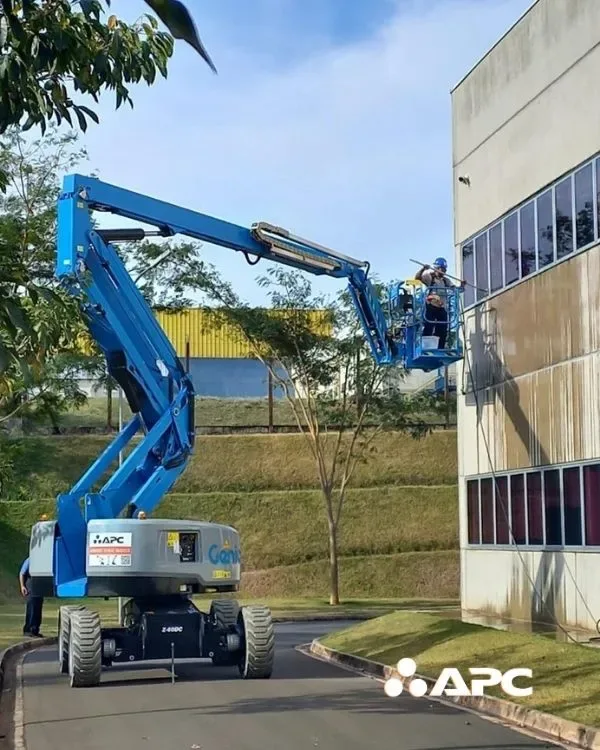 Plataformas Elevatórias Articulada Genie azul. Um trabalho está limpando a fachada de prédio.